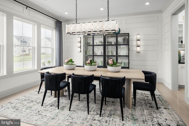 dining area with light wood-type flooring, baseboards, a decorative wall, and recessed lighting