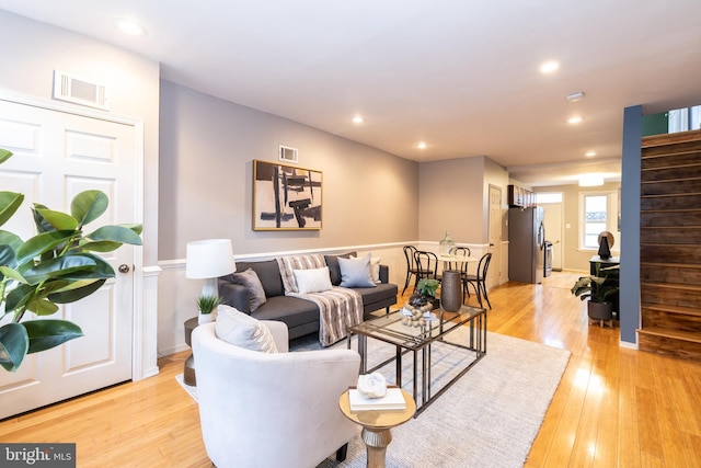 living area featuring stairway, light wood-style flooring, visible vents, and recessed lighting