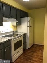 kitchen featuring white appliances, extractor fan, dark wood-style flooring, and light countertops