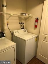 clothes washing area featuring washing machine and dryer, laundry area, and dark wood-style flooring