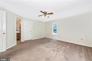 unfurnished bedroom with carpet floors, ceiling fan, baseboards, and connected bathroom