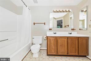 full bathroom with shower / bath combination with curtain, vanity, and toilet