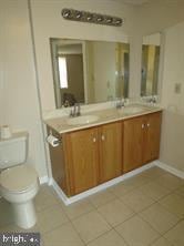 full bathroom with double vanity, tile patterned flooring, toilet, and a sink