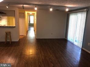 empty room featuring track lighting and wood finished floors