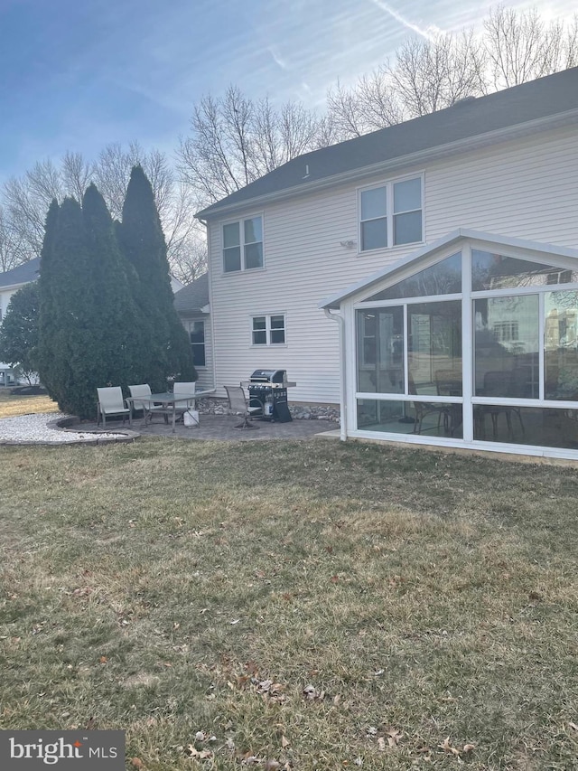 rear view of house featuring a yard, a patio area, and a sunroom