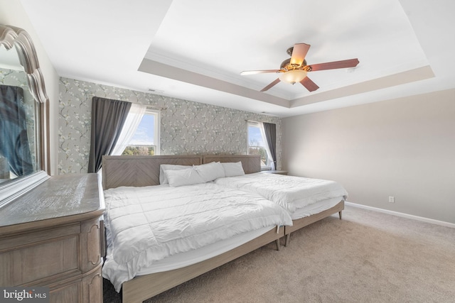 bedroom with a ceiling fan, a raised ceiling, light colored carpet, and baseboards