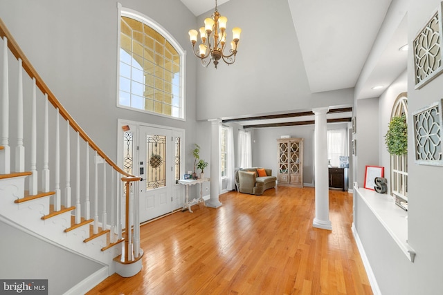 entrance foyer featuring ornate columns, light wood-style flooring, stairs, and baseboards