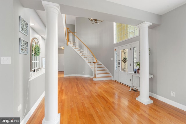 entryway featuring stairs, wood finished floors, decorative columns, and baseboards