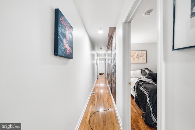 hall with visible vents, baseboards, and wood finished floors