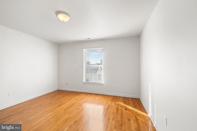 unfurnished room with visible vents, baseboards, and wood finished floors