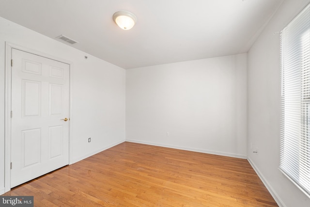 spare room with baseboards, visible vents, and light wood finished floors