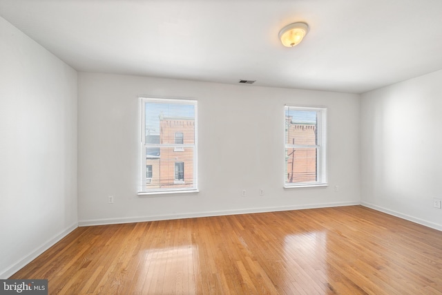 unfurnished room featuring light wood-style flooring, visible vents, and baseboards