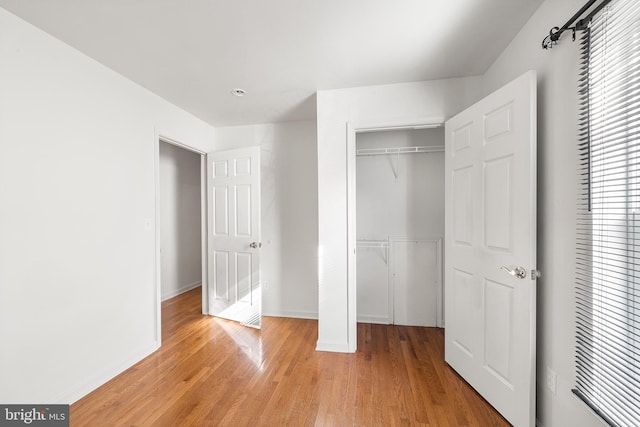 unfurnished bedroom with a closet, light wood-style flooring, and baseboards