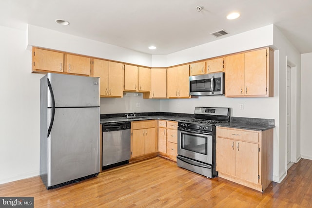 kitchen featuring light wood finished floors, visible vents, dark countertops, appliances with stainless steel finishes, and light brown cabinetry