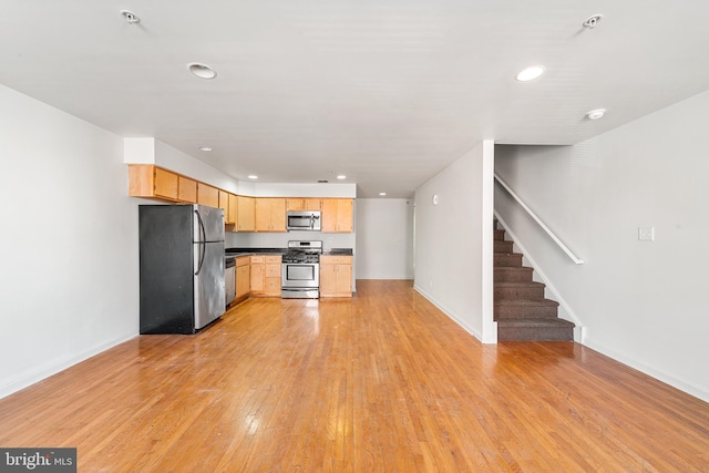 kitchen featuring stainless steel appliances, dark countertops, recessed lighting, light wood-style flooring, and light brown cabinets