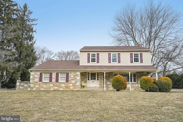 view of front of property featuring stone siding, covered porch, a chimney, and a front lawn