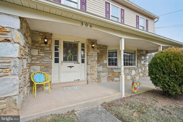 doorway to property featuring stone siding and a porch