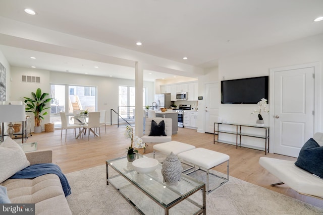 living area with light wood finished floors, visible vents, and recessed lighting