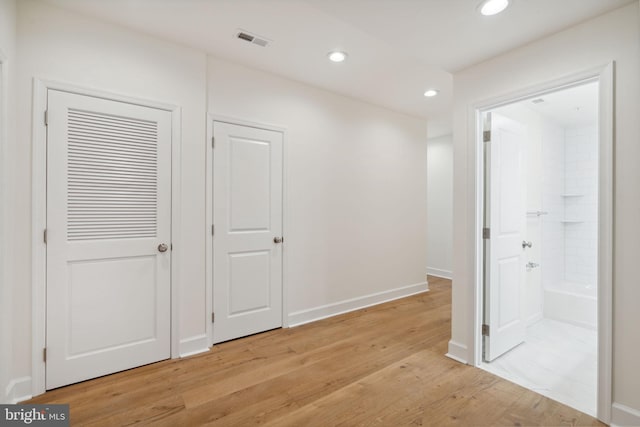 corridor with light wood-style floors, recessed lighting, visible vents, and baseboards