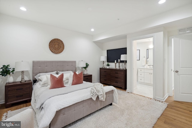 bedroom with baseboards, recessed lighting, connected bathroom, and light wood-style floors