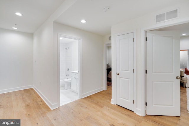 hall with light wood finished floors, baseboards, visible vents, and recessed lighting