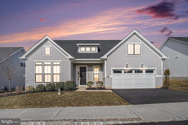 view of front facade with a yard, driveway, a shingled roof, and board and batten siding