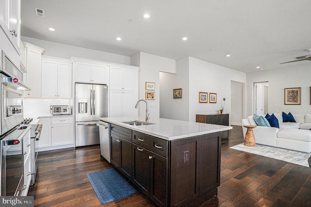 kitchen with dark wood finished floors, a center island with sink, stainless steel appliances, open floor plan, and a sink