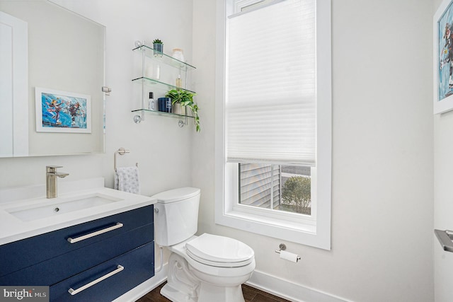 half bathroom featuring baseboards, vanity, toilet, and wood finished floors