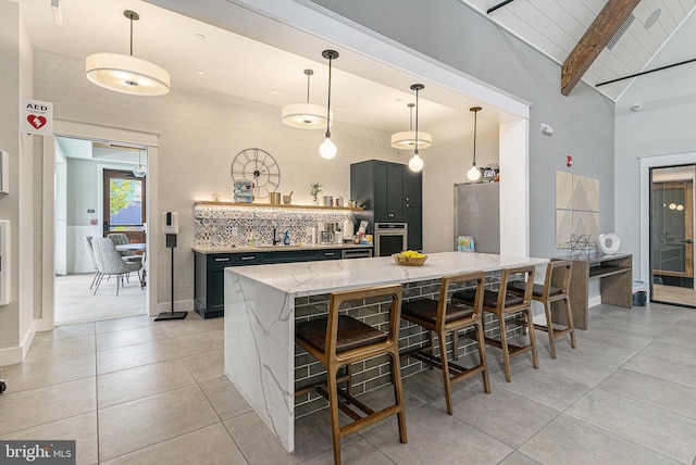 kitchen with light stone counters, a breakfast bar, stainless steel appliances, hanging light fixtures, and a kitchen island