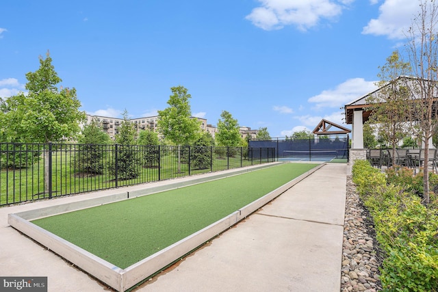 view of home's community featuring a tennis court and fence