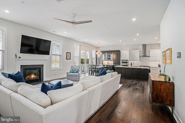 living area featuring a glass covered fireplace, dark wood-style flooring, baseboards, and recessed lighting