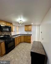 kitchen with dark countertops, black appliances, and brown cabinetry