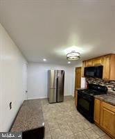 kitchen featuring tasteful backsplash, dark countertops, brown cabinets, and black appliances