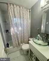 bathroom featuring toilet, vanity, and shower / bathtub combination with curtain