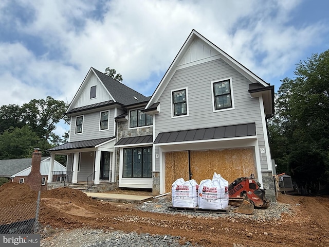 6807 29th St N, Arlington, VA 22213 - view of front of house with a standing seam roof, board and batten siding, stone siding, a metal roof, and a garage