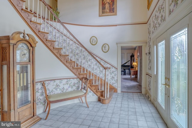 entryway featuring wallpapered walls, a high ceiling, stairs, and light tile patterned floors