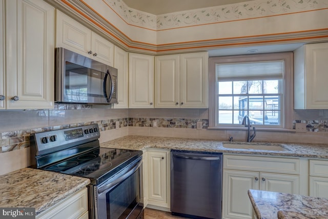 kitchen featuring appliances with stainless steel finishes, tasteful backsplash, a sink, and light stone countertops