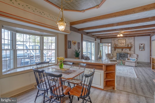 dining area featuring a brick fireplace, light wood finished floors, and baseboards