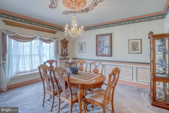 dining area with a chandelier, carpet floors, ornamental molding, and wainscoting