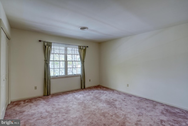 spare room featuring carpet floors, visible vents, and baseboards