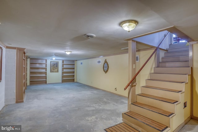 finished below grade area featuring stairway, visible vents, and baseboards