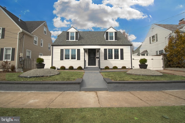 cape cod home with a gate, a front lawn, roof with shingles, and fence