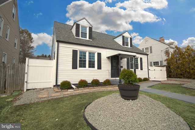 new england style home featuring a shingled roof, fence, a front yard, and a gate