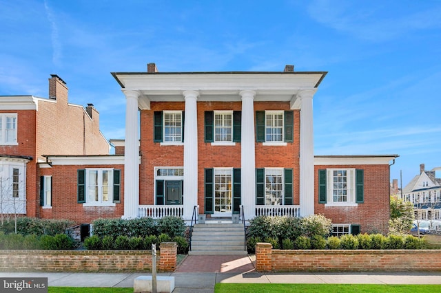 greek revival inspired property featuring brick siding and a porch