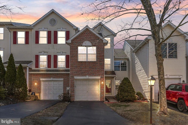 view of front of home with driveway, brick siding, and an attached garage