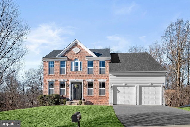 view of front of home with a shingled roof, aphalt driveway, an attached garage, a front lawn, and brick siding