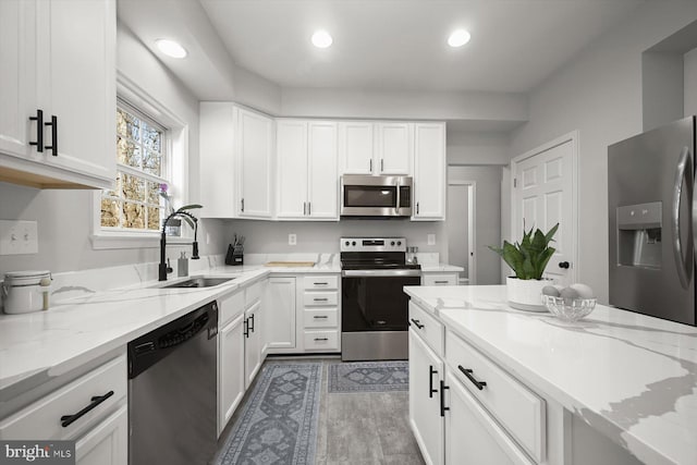 kitchen featuring light stone counters, recessed lighting, appliances with stainless steel finishes, white cabinets, and a sink