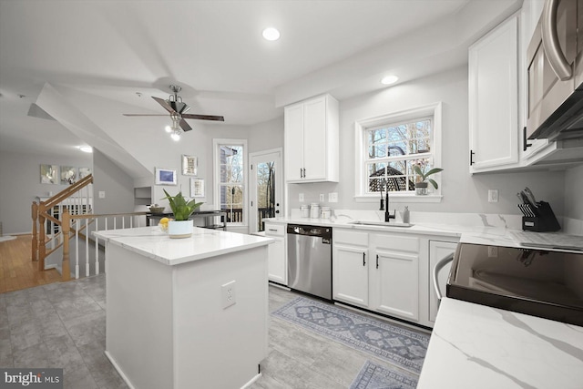 kitchen with white cabinets, light stone counters, stainless steel appliances, a sink, and recessed lighting