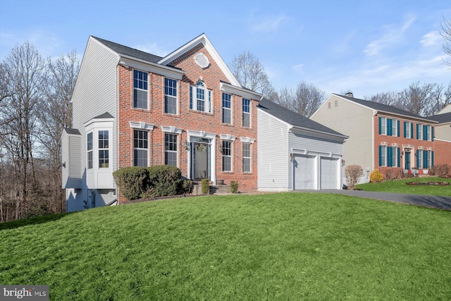 colonial home with a garage, driveway, brick siding, and a front lawn