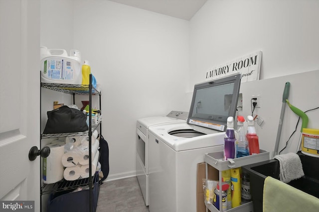 washroom featuring laundry area, baseboards, and washer and dryer